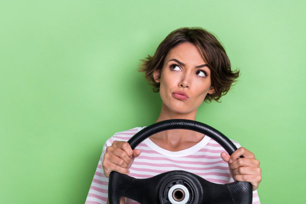 年轻女士的照片肖像，目光空洞，忘记了驾驶规则，穿着时尚的条纹衣服，背景为绿色。图片下载