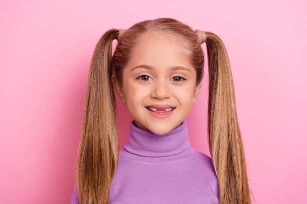 可爱的女孩扎着两个时尚的马尾辫，独自在粉色背景下上幼儿园的照片图片下载