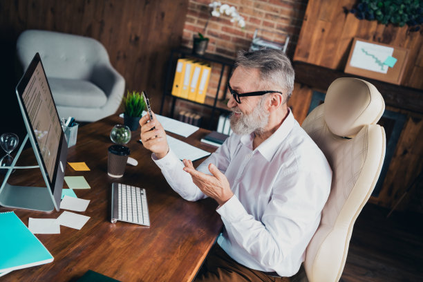 成功的老年男性专家穿着白衬衫，在室内工作站或车间使用现代设备进行交流的照片图片下载