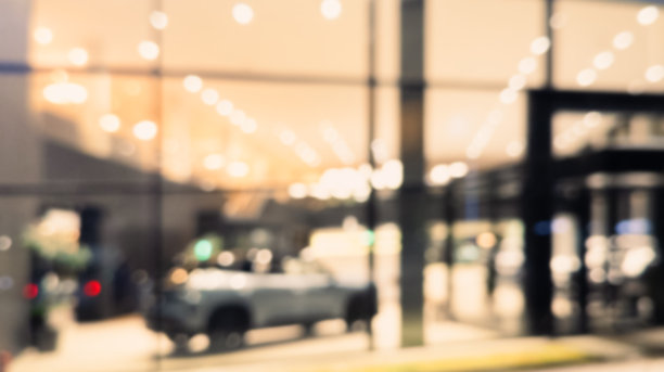 模糊背景的汽车经销商外观。现代建筑汽车展厅的抽象模糊照片。模糊的汽车展厅办公室散景灯光。汽车零售店。图片下载