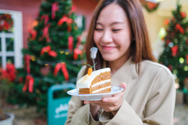 在圣诞派对上，一位女性手持并享用一块胡萝卜蛋糕的肖像照片图片下载