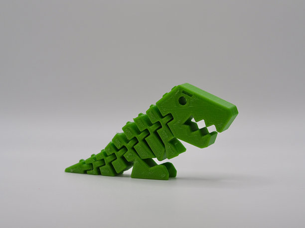 这张图片展示了一款生动的绿色3D打印恐龙玩具，摆出俏皮而动感的姿势，体现了创意和现代打印技术的创新。图片下载