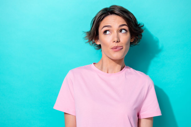 特写照片：年轻可爱漂亮的女性，调皮地吐舌头，表现出好奇和有趣的神情，背景为青色，空白区域。图片下载