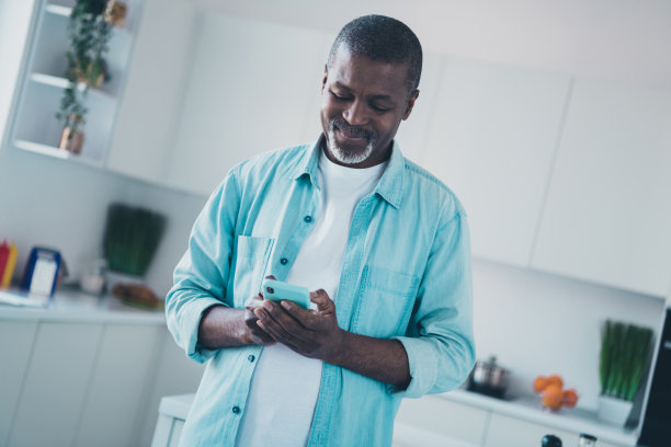 积极的老年男性在现代厨房中使用智能设备阅读新闻评论反馈的照片图片下载