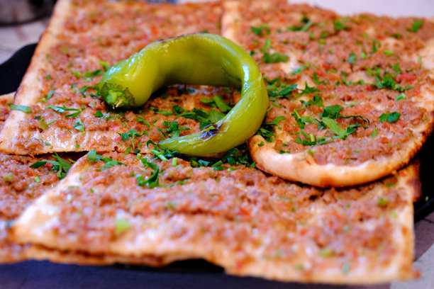 传统土耳其美食科尼亚肉饼的特写照片，切片并配有青椒。图片下载