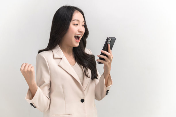 年轻美丽的亚洲女性的肖像照片，感到快乐或惊讶，手中拿着黑色空白屏幕的智能手机，背景为白色，可用于广告或产品展示概念。图片下载