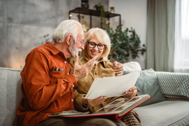 老年夫妇坐在沙发上翻看家庭照片册图片下载