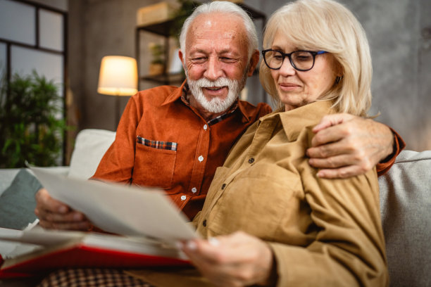 老年夫妇坐在沙发上翻看家庭照片册图片下载