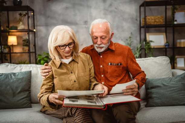 老年夫妇坐在沙发上翻看家庭照片册图片下载