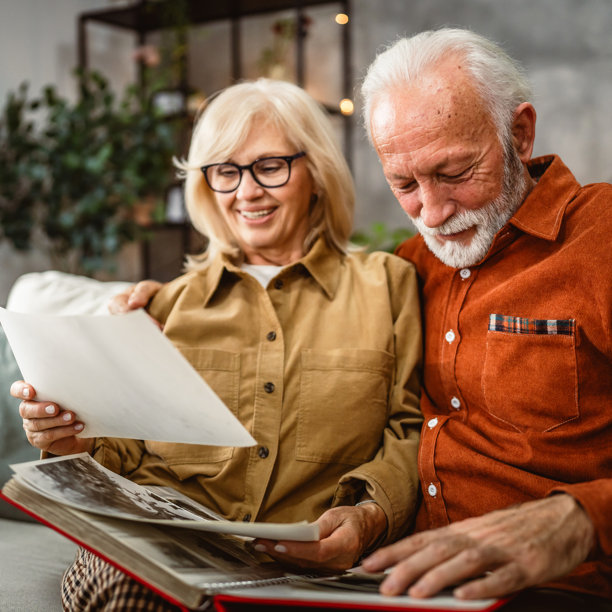 老年夫妇坐在沙发上翻看家庭照片册图片下载