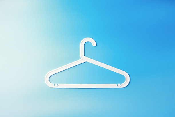 白色塑料衣架的俯视极简风格照片，背景为白色和蓝色。平铺展示用于悬挂衣物的衣架。极简趋势布局，生活方式或室内设计内容。图片下载