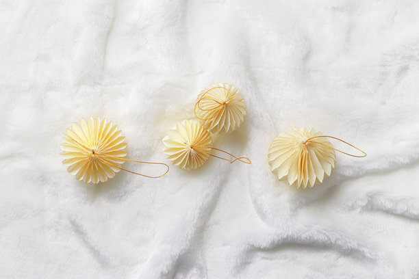 平铺的纸质新年装饰品，金色米色圣诞球放在白色人造毛皮背景上，冬季节日静物。极简风格照片，优雅的节日装饰，俯视图。图片下载