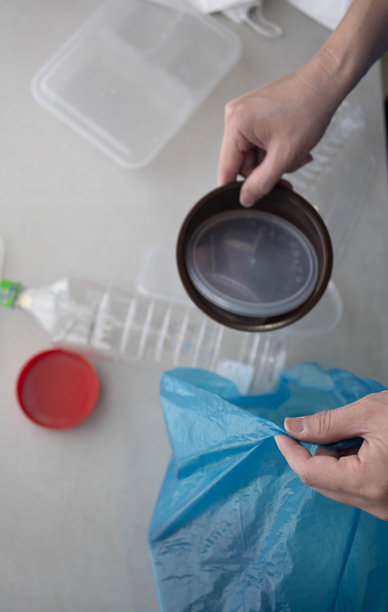 一名男子挤压塑料瓶并将其放入塑料袋中进行回收，以保护环境的库存照片图片下载