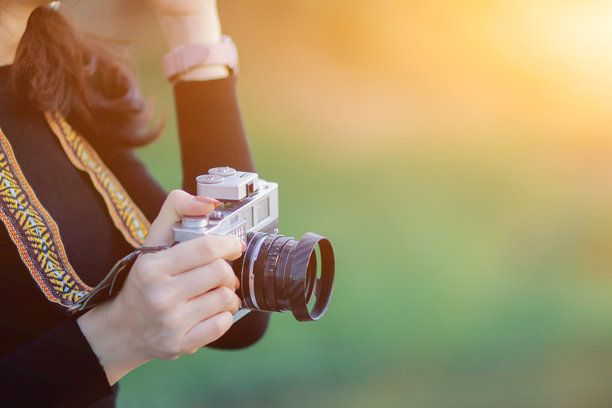 女性游客手持胶卷相机，在桥上走动拍照，捕捉旅游城市的氛围，胶卷相机带来复古风格。年轻女性正在用胶卷相机记录照片。图片下载
