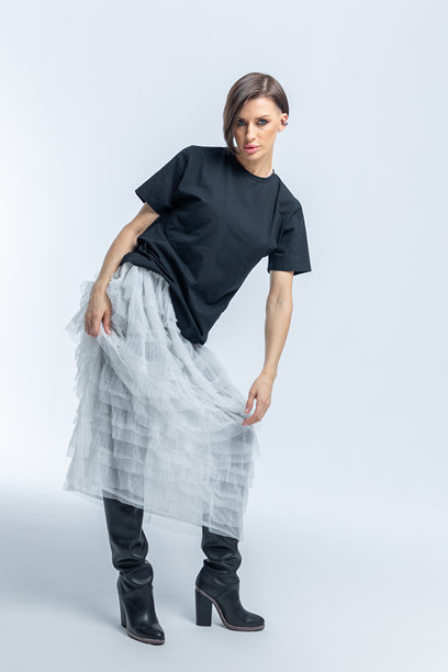 身穿黑色毛衣、浅灰色裙子的美丽模特，背景为白色。高端时尚。竖版照片。图片下载