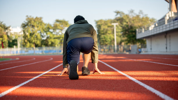 一位强壮的运动员穿着运动服在早晨的体育场训练的特写照片。图片下载