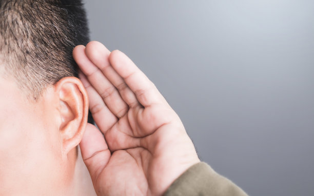 一个人用手捧住耳后，表示听力困难的特写。这张图片突显了听力损失的挑战以及耳朵健康意识的重要性。图片下载
