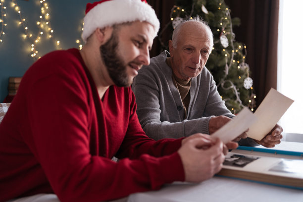 成年儿子与年迈父亲在圣诞节回忆旧照片图片下载