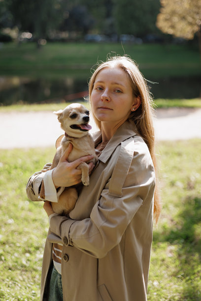 年轻女性在公园散步时抱着小狗。高质量照片图片下载