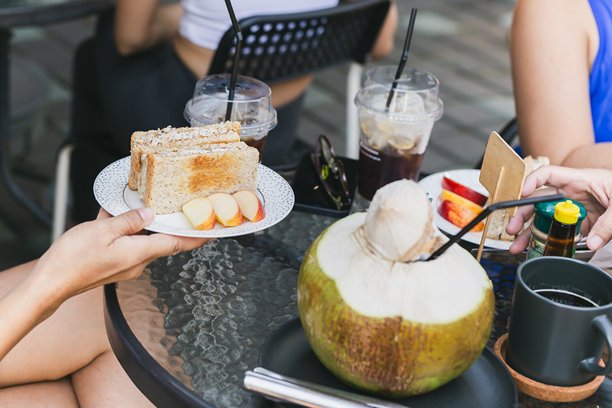 女人在咖啡馆里用手拿着白盘上的金枪鱼三明治。图片下载