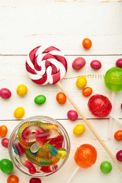 不同种类的糖果放在白色木质背景上，留有空白空间。五彩缤纷的生日派对背景。竖版照片图片下载
