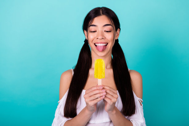 穿着露肩上衣的可爱女孩在青色背景下享受冰镇水果汁的照片图片下载