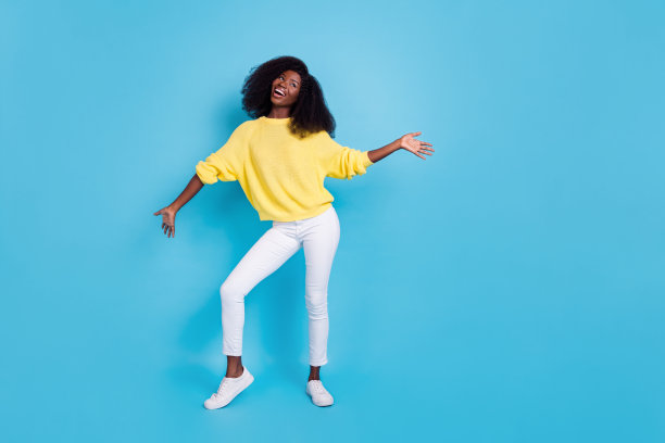 年轻快乐的女士在蓝色背景下跳舞，展现派对放松的舞姿的全身照片图片下载