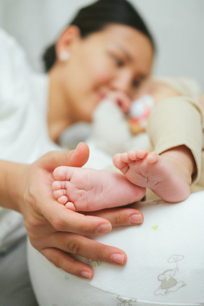 母亲的手掌托着新生亚洲婴儿的脚。特写家庭照片，展示孩子的脚趾、脚跟和脚部。图片下载