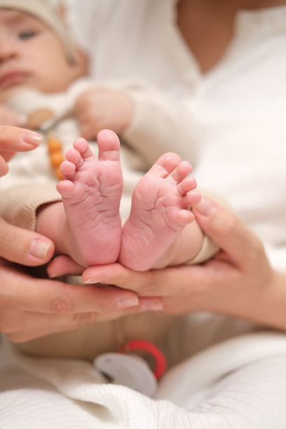 母亲的手掌托着新生亚洲婴儿的脚。特写家庭照片，展示孩子的脚趾、脚跟和脚。图片下载