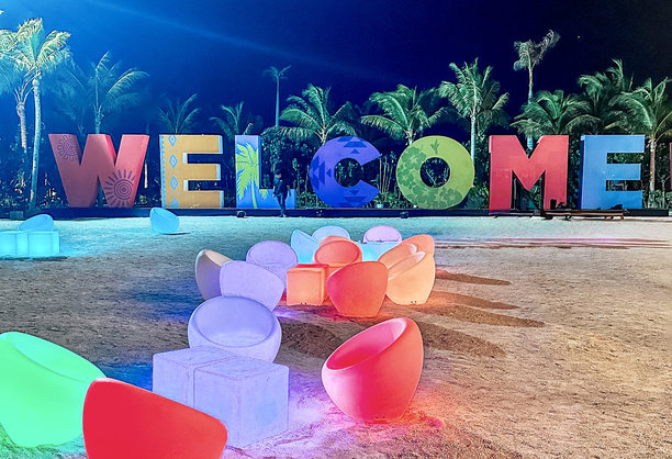 这张生动的照片展示了一个色彩斑斓的户外布置，中央有一个大型发光的“欢迎”标志。图片下载
