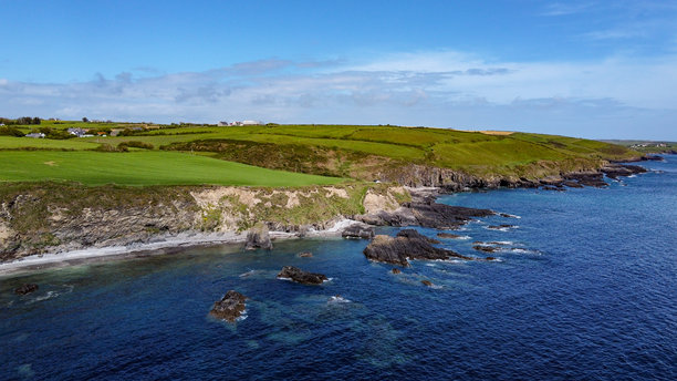 阳光明媚的春天，亚特兰大洋上的绿色山丘。海岸上方的蓝天。爱尔兰西科克的海岸线。无人机拍摄的照片。图片下载