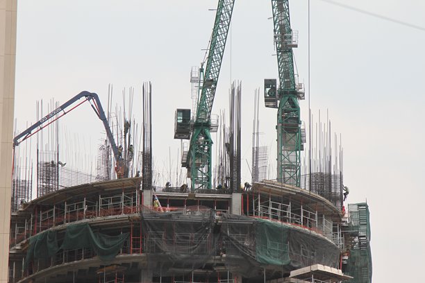 建筑工地的工作日。工人在高处，钢梁、起重机和电缆。照片拍摄于阳光明媚的日子。图片下载