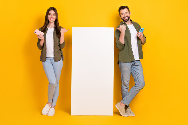 积极的人们在黄色背景上展示巨大的手机广告横幅的全身照片图片下载