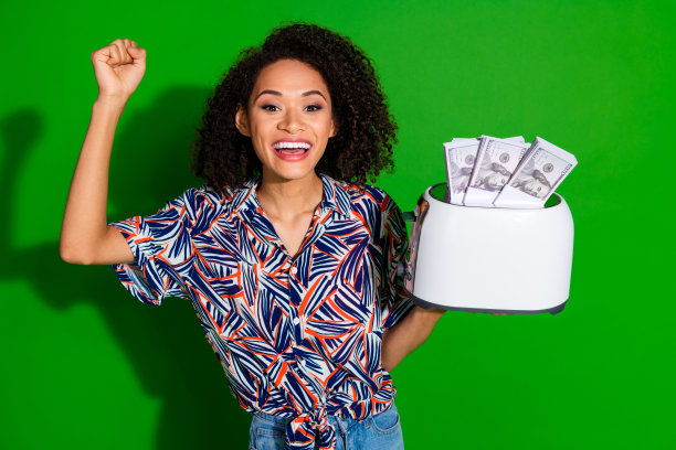 可爱的年轻女士在绿色背景下穿着时尚多彩的服装，手持烤面包机和奖金，拍摄的肖像照片。图片下载