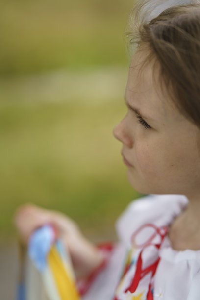 小女孩穿着传统的乌克兰刺绣衬衫，手持花环，站在乡村道路上的竖版照片图片下载
