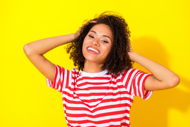 年轻迷人、顽皮有趣的女性在黄色背景下触摸头发的特写照片图片下载