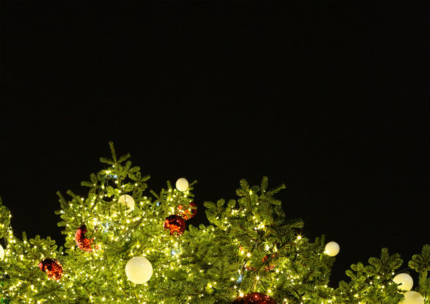 装饰有红白色花环和圣诞球的圣诞树，背景是夜空。氛围照片。黑色背景。图片下载