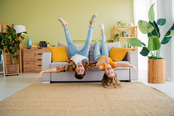 年轻情侣在现代明亮的春季舒适室内公寓里，倒着躺在沙发上享受时光的全身照片图片下载