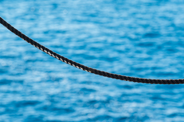 极简、创意和艺术感的图片，黑色绳索上有白色涂料，背景是青绿色的水。图片下载