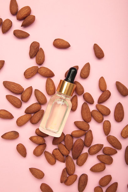 新鲜的杏仁油与杏仁坚果在粉色背景上。垂直照片。图片下载