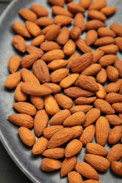 新鲜天然健康的杏仁坚果放在黑色盘子上。垂直照片。图片下载