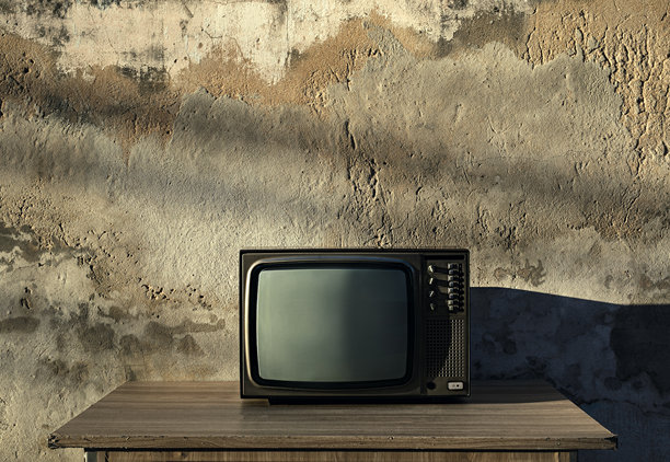 复古老电视机放在木桌上，屏幕空白，前面是古老的砖墙。古董和复古风格的照片图片下载