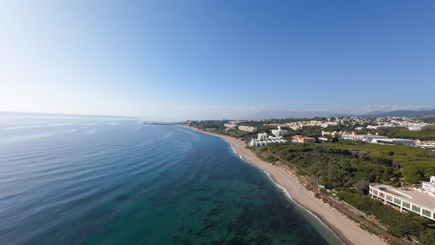 西班牙米哈斯的卡拉霍达小镇美丽海滩的航拍照片，展示了12月阳光明媚的日子里，从空中俯瞰的沙滩和海滨公寓。图片下载