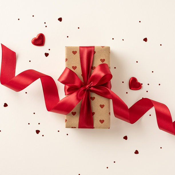 一张正方形的照片，精美包装的礼物上系着红色丝带，周围环绕着小心形装饰，唤起了爱的和庆祝的感觉。图片下载