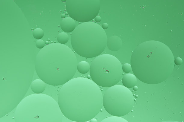 宏观照片，水面上的油滴圆圈。抽象的绿色背景与油泡。图片下载
