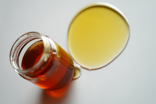 玻璃罐中的蜂蜜，盖子打开，蜂蜜正在流出。高分辨率商业用途库存图片。图片下载