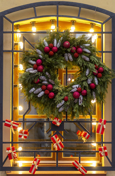 窗户装饰着圣诞节的装饰，有新年花环、球、松果和红色礼盒。竖版照片图片下载