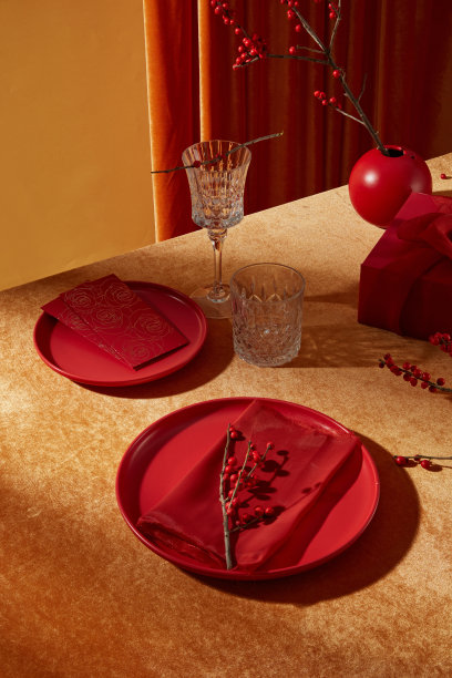 关于中国新年的垂直框架照片。一些红色餐具摆放在黄色桌子上，旁边有一个红色礼品盒和花瓶。高角度视图，留有空白空间用于产品展示。图片下载