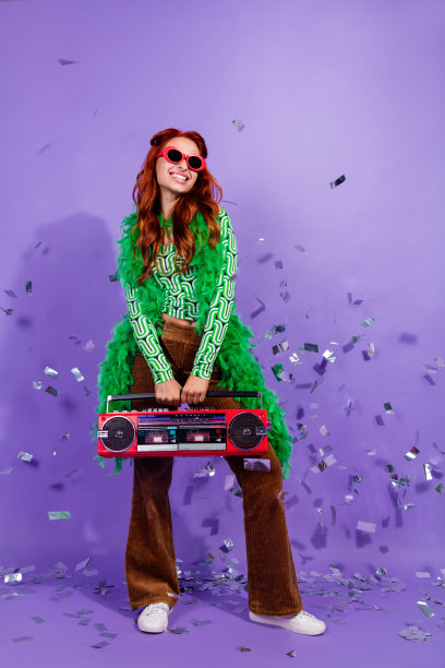 时尚年轻女性在充满活力的派对场景中手持复古音响，竖版照片图片下载