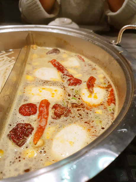 美味的辛辣火锅，在餐厅享受美食，中式和日式热汤，盘子里的牛肉和猪肉切片，肉类蘸酱，传统美食库存照片图片下载